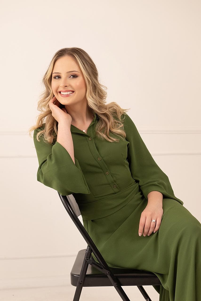 Gabriela Bayerl sentada em retrato profissional com roupa verde